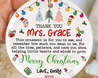 May include: A white Christmas ornament with a gold string, featuring colorful illustrations of Christmas trees, a Santa hat, and a pencil. The text reads "Thank You Mrs. Grace" and "Merry Christmas", with a message from "Love, Emily" and the year "2025".