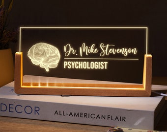 May include: A wooden desk lamp with a clear acrylic panel featuring a stylized brain graphic and the text "Dr. Mike Stevenson PSYCHOLOGIST".
