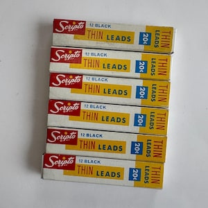 May include: A stack of six vintage Scripto Thin Leads boxes. Each box is white with red and yellow accents, and features the text "Scripto", "12 Black", and "Thin Leads". The price is marked as 20¢.