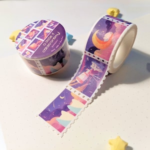 Pu&ograve; includere: Un rotolo di nastro washi viola e bianco con un motivo ripetuto di stelle, lune e pianeti. Il nastro ha la scritta "a little astronomy" stampata su di esso.