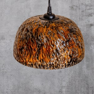 May include: A brown and black ceramic pendant light fixture with a textured surface.