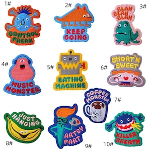 May include: A selection of ten embroidered patches with cartoon monster designs and slogans. The patches are in vibrant colours like blue, orange, green, and yellow. Each patch has a unique design and text, including "Control Freak" and "Keep Going".