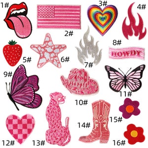 May include: A selection of pink embroidered patches with diverse designs: a tongue, an American flag, a heart, flames, a butterfly, a cowboy hat, a cheetah, a cowboy boot, and flowers. Patches are numbered.