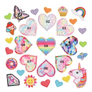 May include: A selection of colourful embroidered patches in various shapes, including hearts, a butterfly, a cupcake, a rainbow, a donut, a diamond, a flower, a dragonfly, and a unicorn. The heart patches have different patterns and numbers.