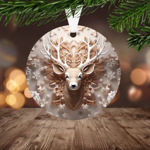 May include: A round, white, and brown Christmas ornament featuring a deer head with antlers in a paper cut-out style. The deer head is surrounded by white snowflakes and brown paper cut-out designs.