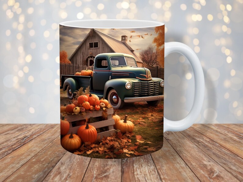May include: White ceramic mug featuring a fall scene with a vintage teal pickup truck loaded with pumpkins. A wooden crate overflowing with pumpkins sits in front of the truck. The background shows a barn and autumn foliage.