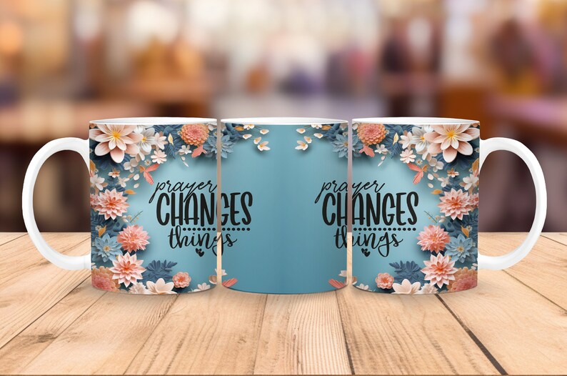 K&ouml;nnte beinhalten: Drei wei&szlig;e Keramikbecher mit blauem Hintergrund und floralem Design. Die Becher haben den Text "prayer changes things" in schwarzer Schrift.