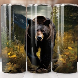 May include: A black bear walks through a forest with a background of green trees and yellow leaves. The bear is in focus and the background is blurred.
