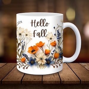 Op de afbeelding: Witte keramische mok met een bloemenontwerp met oranje, witte en blauwe bloemen. De mok heeft de tekst "Hello Fall" op de voorkant.