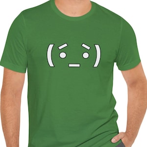 May include: A green t-shirt with a white text graphic of a simple emoticon with a confused expression. The emoticon has two dots for eyes and a horizontal line for a mouth.