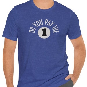 May include: Blue crew neck t-shirt with the text "DO YOU PAY THE 1" in white lettering. The number 1 is inside a gray circle. The shirt is made of a soft, comfortable material.