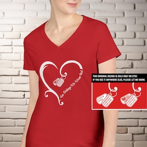 Könnte beinhalten: Rotes V-Ausschnitt-T-Shirt mit weißem Herzdesign und dem Text "On Fridays We Wear Red". Im Herzen befinden sich zwei Hundemarken-Illustrationen. Das Shirt hat auch den Text "Remember Everyone Deployed".