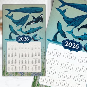 May include: 2026 calendar featuring illustrations of whales in shades of blue. The calendar includes the months of the year, with each month's days clearly displayed. The design has a vintage aesthetic, with a light blue background.
