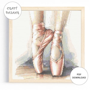 May include: A cross-stitch pattern of a pair of pink ballet shoes. The shoes are tied together and the pattern is in a wooden frame.