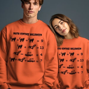 May include: Two orange sweatshirts with a Halloween-themed math problem printed on the front. The problem features black cats, bats, and pumpkins. The text on the sweatshirts reads "Math Vintage Halloween".