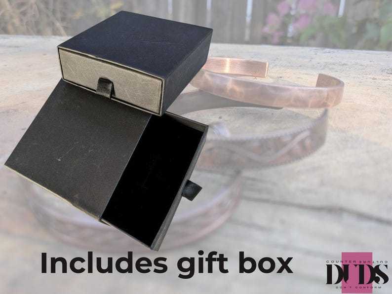 May include: A black gift box with a drawer, open to reveal a black interior. The box is sitting on a wooden surface. Includes gift box.