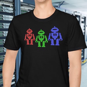 May include: Black crew neck t-shirt featuring three colorful robot figures. The robots are red, green, and blue, and are arranged in a row across the front of the shirt. The robots have a simple, blocky design.