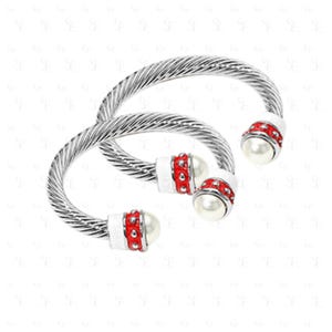 May include: Two silver-toned, twisted-cable bracelets. Each bracelet features a white end cap with red accents and a faux pearl. The bracelets are displayed on a white background.