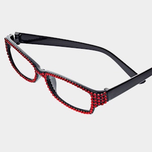 Peut inclure: Lunettes de lecture &agrave; monture noire orn&eacute;es de strass rouges sur les bords. Les lunettes ont une monture demi-cercl&eacute;e et des verres transparents. Les strass ajoutent une touche d'&eacute;clat &agrave; la monture.