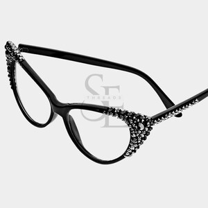 May include: Black cat-eye glasses with clear lenses. The frames are embellished with small, dark rhinestones along the top and outer edges. The arms are thin and black. The image has the text "GF THREADS" in the center.