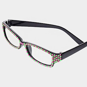 Peut inclure: Lunettes de lecture &agrave; monture noire avec verres rectangulaires. Les montures sont orn&eacute;es de strass roses et verts. Les lunettes ont un design classique avec une touche moderne et color&eacute;e, adapt&eacute;es &agrave; un usage quotidien.