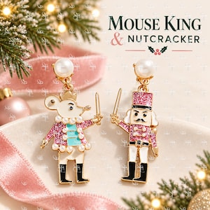 May include: A pair of gold-tone drop earrings featuring a Mouse King and a Nutcracker character. Each earring has a white pearl stud top, pink glitter accents, and enamel detailing. The text MOUSE KING & NUTCRACKER is visible in the background.