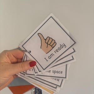 May include: A set of white cards with black borders, held together by a metal ring. The top card shows a thumbs-up hand gesture and the text "I am ready". Other cards are visible with partial text.