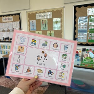 May include: A pink-framed visual aid with the words "I want" and icons representing various activities and items. Icons include bubbles, playdough, rice, ear defenders, drink, kinetic sand, walk, snack, book, puzzle, calm corner, blanket, fidgets, and sensory feel.