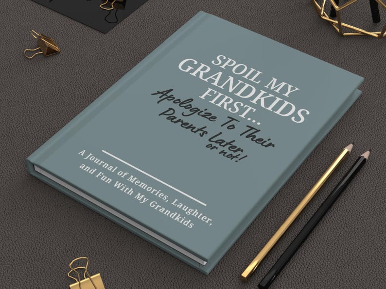 Peut inclure: Un journal bleu sarcelle avec le texte "SPOIL MY GRANDKIDS FIRST... Apologize To Their Parents Later or not!" et "A Journal of Memories, Laughter, and Fun With My Grandkids." Des crayons dor&eacute;s et noirs et un trombone dor&eacute; sont &eacute;galement visibles.