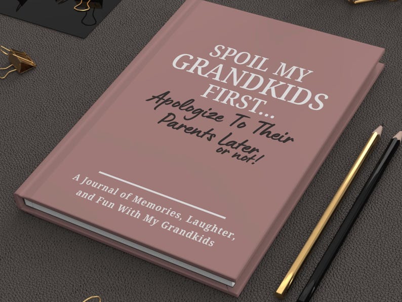 Peut inclure: Un journal mauve avec le texte "SPOIL MY GRANDKIDS FIRST... Apologize To Their Parents Later, or not!" et "A Journal of Memories, Laughter, and Fun With My Grandkids." Des crayons dor&eacute;s et noirs sont &agrave; c&ocirc;t&eacute; du journal.