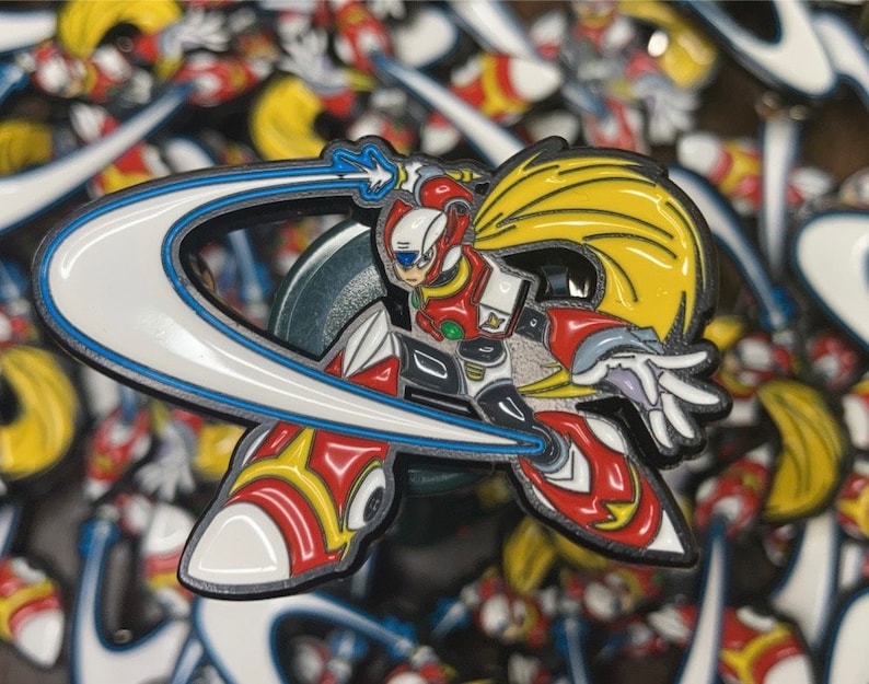 Op de afbeelding: Een rode en gele emaille pin met een robotpersonage met een blauw en wit halvemaanvormig energiemes. De robot heeft een rood en wit helm, een rode borstplaat en een gele cape.
