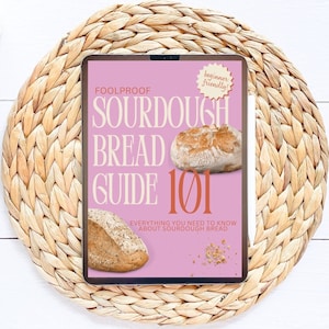 Könnte beinhalten: Ein rosa digitales Tablet mit einer Hülle, auf der "Foolproof Sourdough Bread Guide 101" steht, mit einem Aufkleber "Anfängerfreundlich". Die Hülle zeigt zwei Sauerteigbrote.