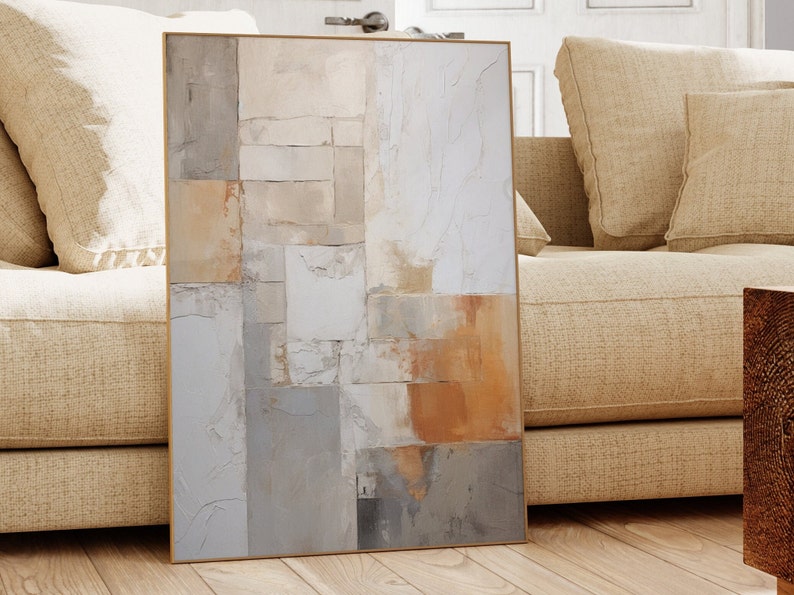 May include: Abstract art print with a geometric design in shades of beige, gray, and brown. The print is framed in a thin, gold frame.