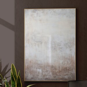 May include: Abstract painting with a white, grey, and brown colour scheme. The painting is framed in a gold frame.