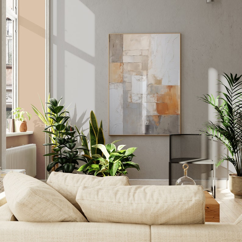 May include: A beige couch with two pillows in a living room with a large abstract painting on the wall, a potted plant, and a black metal chair.