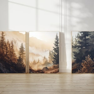 以下が含まれることがあります： 霧がかかった背景の森林のシーンを描いた、額縁付きの水彩画3点。絵画は茶色、緑、青の色合いで描かれています。