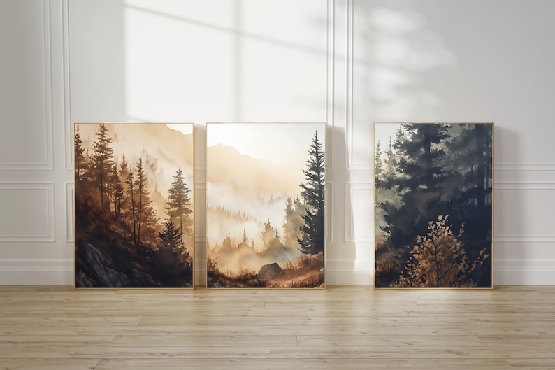 以下が含まれることがあります： 霧がかかった背景の森林のシーンを描いた、額縁付きの水彩画3点。絵画は茶色、緑、青の色合いで描かれています。