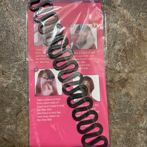 May include: A black plastic French braiding tool with multiple loops. The tool is packaged on a pink background with instructions on how to use it. The packaging also includes the text "French Braiding Tool" and "Made in China".