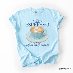 A flat lay of a Chambray Comfort Colors shirt with a design featuring an espresso and the phrase More Espresso Less Depresso.