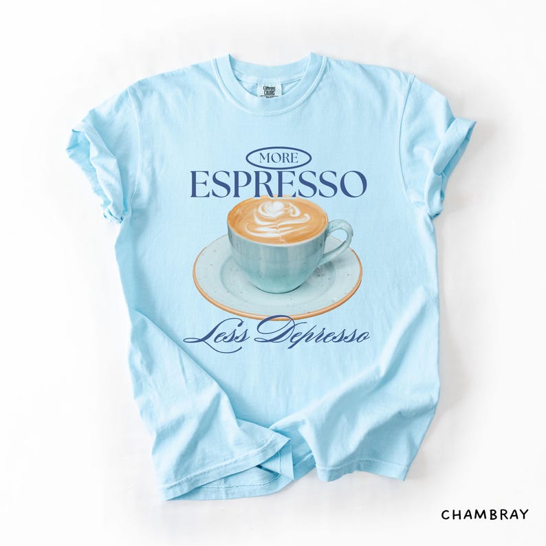 A flat lay of a Chambray Comfort Colors shirt with a design featuring an espresso and the phrase More Espresso Less Depresso.