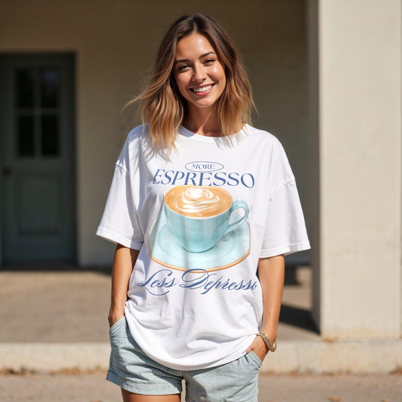 May include: White oversized t-shirt with a graphic of a blue coffee cup with a latte design and the text "More Espresso Less Depresso".