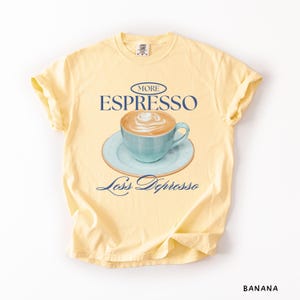 A flat lay of Butter Comfort Colors shirt with a design featuring an espresso and the phrase More Espresso Less Depresso.