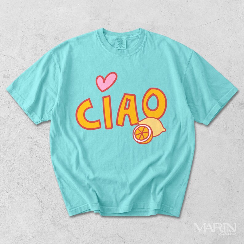 K&ouml;nnte beinhalten: Ein t&uuml;rkisfarbenes T-Shirt mit dem Wort "CIAO" in orangefarbenen Buchstaben mit gelber Umrandung, einem rosa Herz und einer Zitronenillustration. Das Shirt besteht aus weichem Material und hat kurze &Auml;rmel.