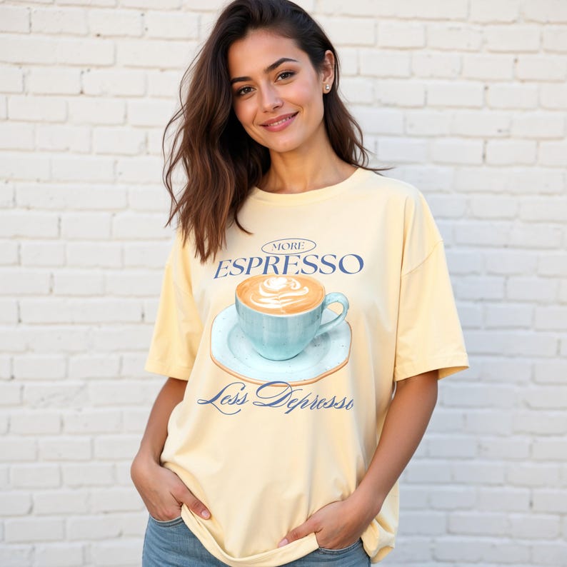 May include: A yellow t-shirt with a graphic of a blue coffee cup with a white foam design. The text on the shirt reads "More Espresso Less Depresso".