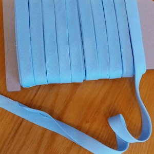May include: A roll of light blue elastic fabric, folded and stacked, with a single piece of the fabric extending out to the right.