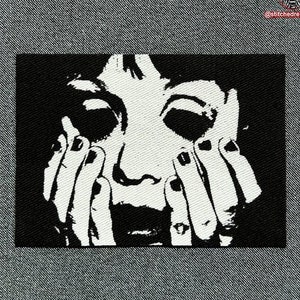 Puede incluir: Parche bordado en blanco y negro de la cara de una mujer con las manos cubriéndole la boca, gritando.