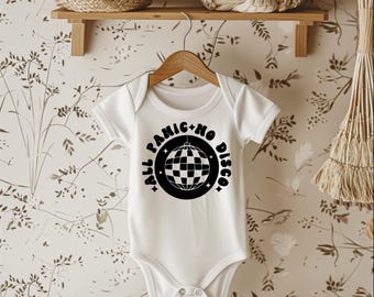 May include: White baby onesie with the text "ALL PANIC + NO DISCO" in a black circular design with a disco ball graphic. The onesie is hanging on a wooden hanger.