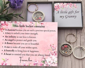May include: A pink and white floral card with the text "This little locket contains" and a list of reasons why the locket is special. The card is next to a silver locket keychain with a small butterfly charm. The text "A little gift for my Granny" is on a separate card.