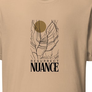 Op de afbeelding: Een beige t-shirt met een zwart en gouden grafisch ontwerp. De grafiek toont een gestileerde zon en een boom met de tekst "RESURRECT NUANCE" eronder.