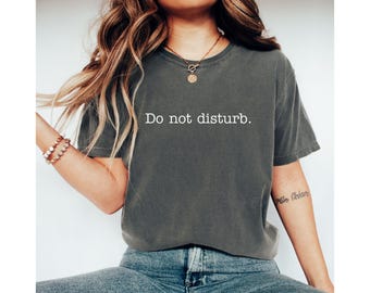 Könnte beinhalten: Ein dunkelgraues T-Shirt mit dem Aufdruck "Bitte nicht stören" in Weiß auf der Vorderseite.